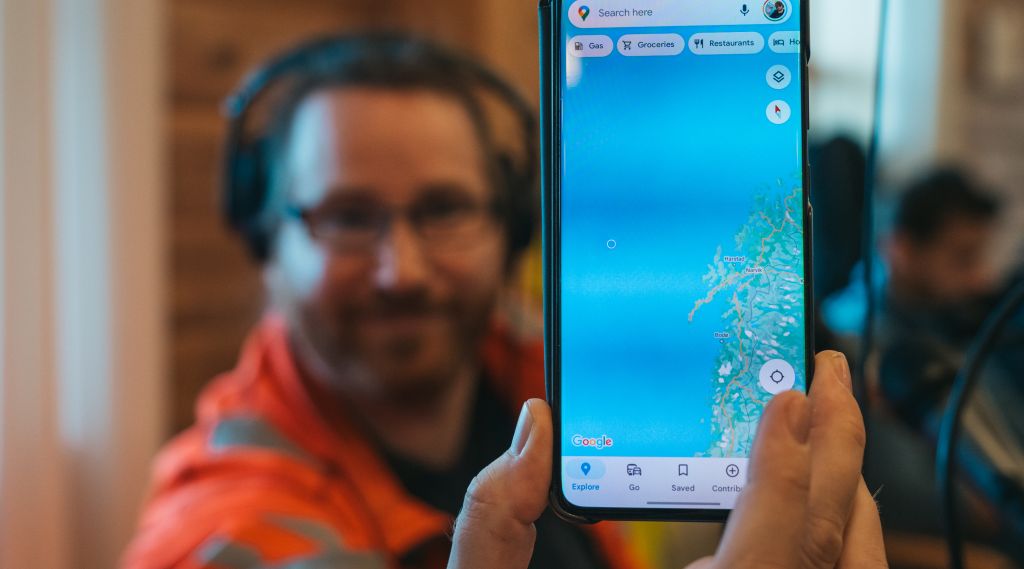 Mann holder opp en mobiltelefon med kart.