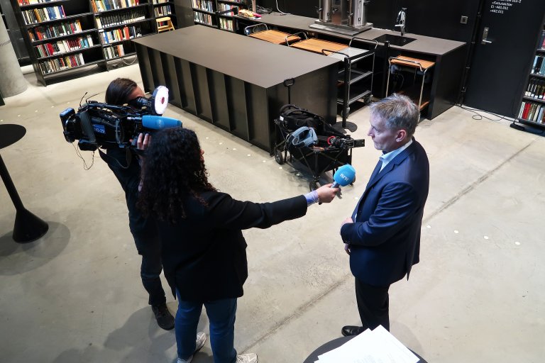 forskningsdirektør Espen Skjelland i samtale med en NRK journalist mens en kameramann filmer