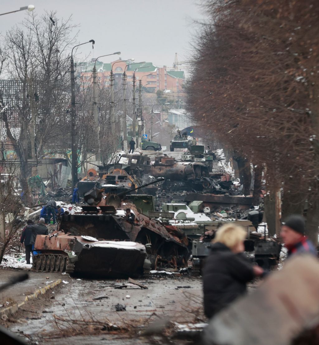 People look at the gutted remains of Russian military vehicles on a road in the town of Bucha, close to the capital Kyiv, Ukraine, Tuesday, March 1, 2022