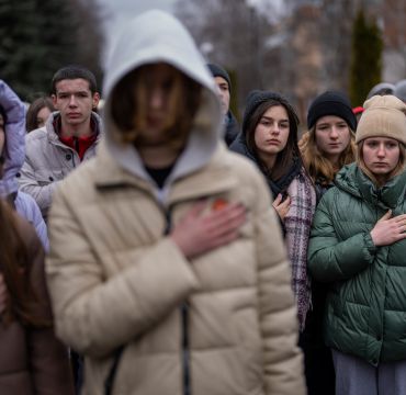 Sørgende ungdommer holder hånden til hjertet mens den Ukrainske nasjonalsangen spilles i en begravelse.