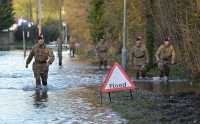 soldater som vasser i vann i gater med et fareskilt som viser 