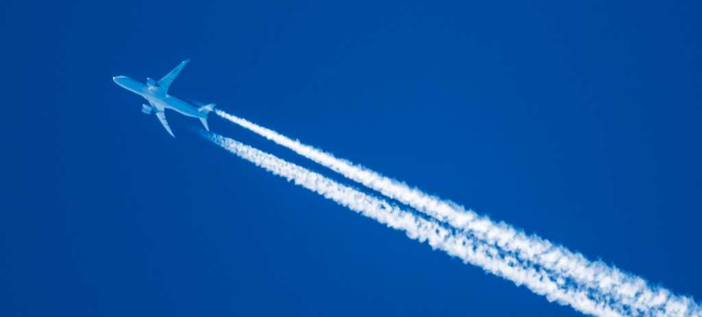 Fly med kondensstriper. Blå himmel.