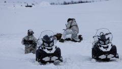 Tre soldater med snøscooter. Finnmarksvidda. Snø. En holder vakt, en annen speider etter fiender.