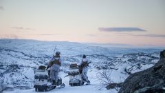 To soldater med vinterkamuflasje på snøscooter. Utsikt over vinterlandskap i Finnmark.