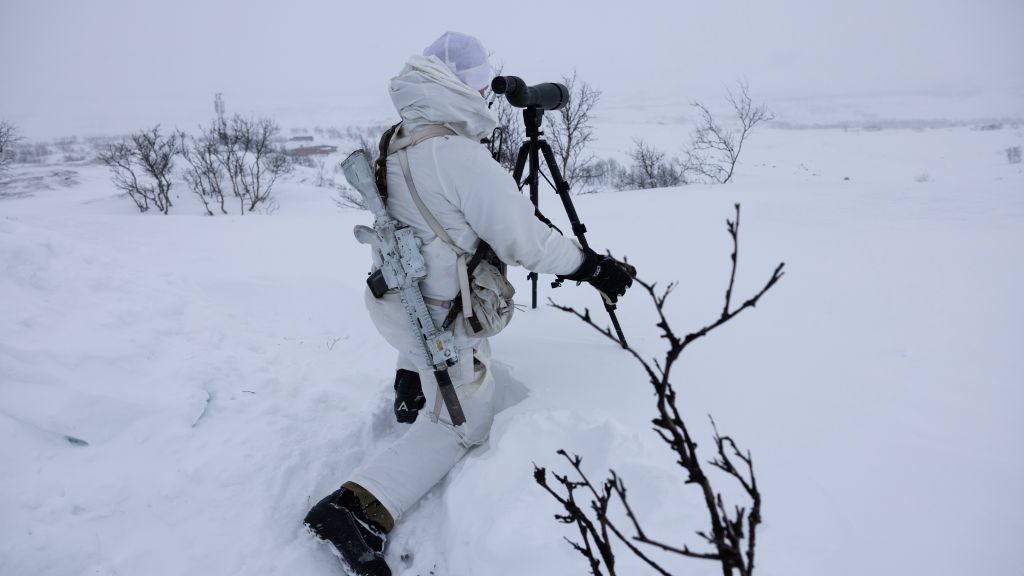 Soldat i vinterkamuflasje speider med en kikkert. Finnmarksvidda. Vinter. 