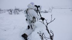Soldat i vinterkamuflasje speider med en kikkert. Finnmarksvidda. Vinter. 