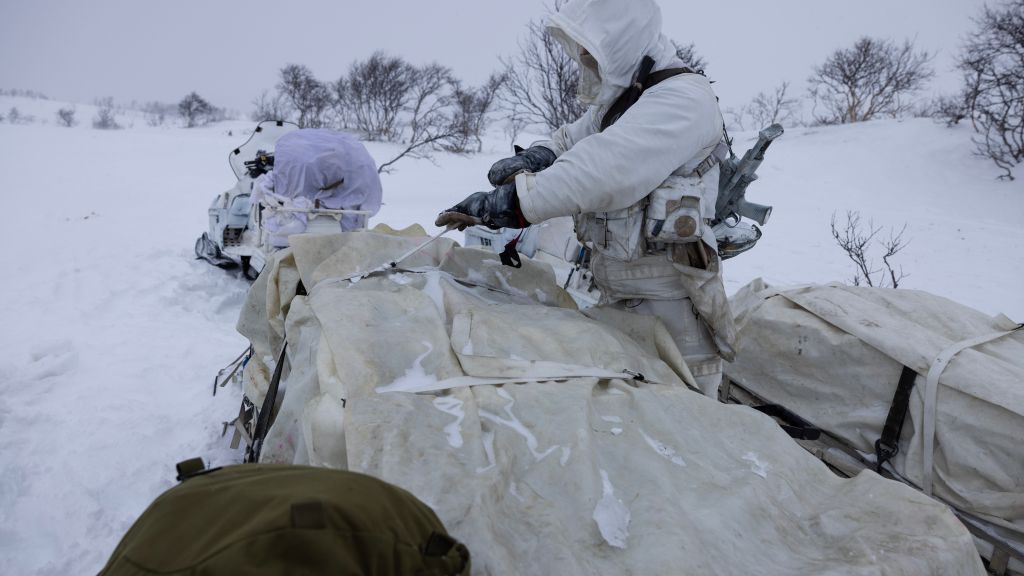 Bilde fra Halkavarre skytefelt i Finnmark. Snøføyk. Soldater er delvis skjult bak en bakketopp.