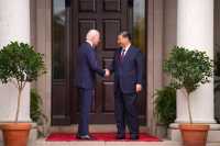 Presidentene fra USA og Kina håndhilser foran en stor tredør.