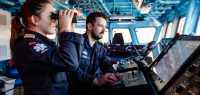 To offiserer på broen til KNM Otto Sverdrup. En kvinne med kikkert og en mann som ser på en skjerm.