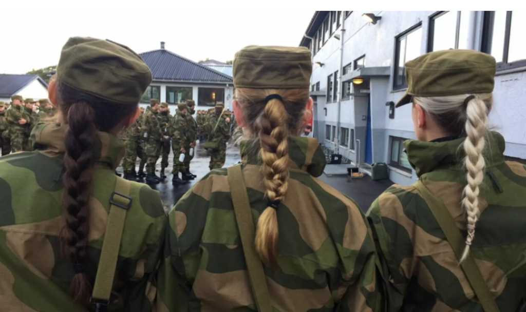 Vi ser ryggene til tre kvinner i hærens militære kamuflasjeuniform. de står skulder til skulder og alle tre har lange fletter som henger ned.