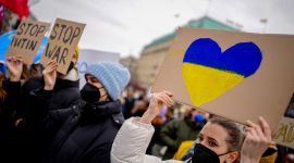 kvinne holder opp en plakat under en demonstrasjon med et hjerte med de ukrainske fargene