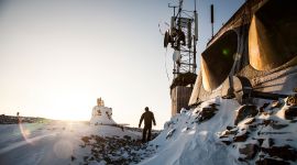 Radarutstyr i vinterlandskap med to personer i siluett. Foto