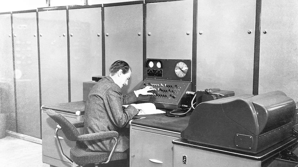 Harald Keilhau sitter ved FFIs første digitale datamaskin med 2000 vakuumrør og 20 kW varmetap. Ferranti Rapid Electronic Defence Research Institute Computer (FREDRIC) representerte et gjennombrudd i hvordan forskerne løste kompliserte matematiske problemer. 