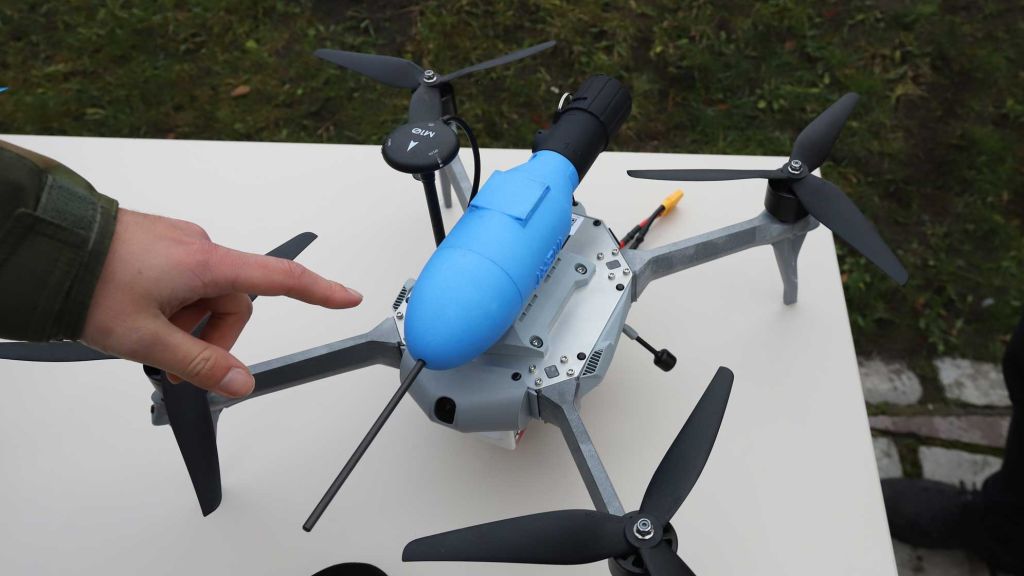 Drone med en blå beholder på toppen.