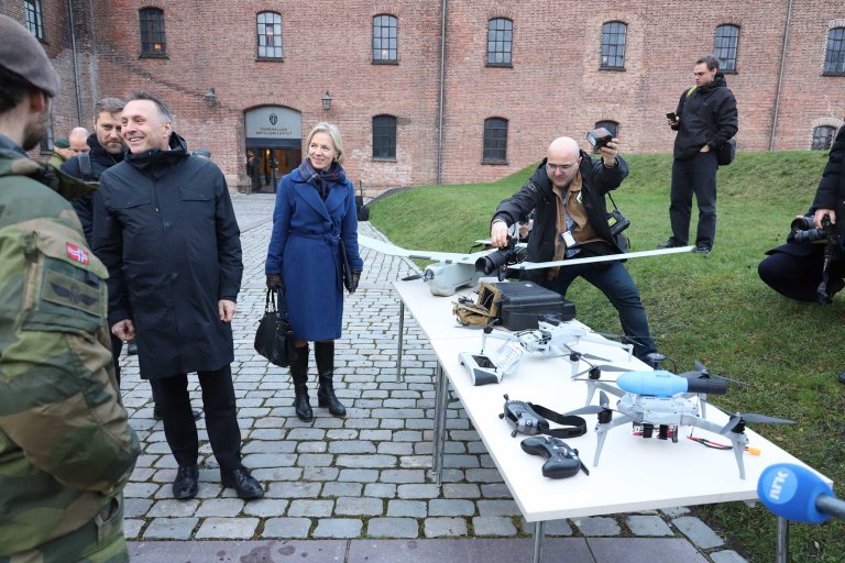 Et utvalg droner på et bord på brosteinen foran Fanehallen. Flere folk står rundt.