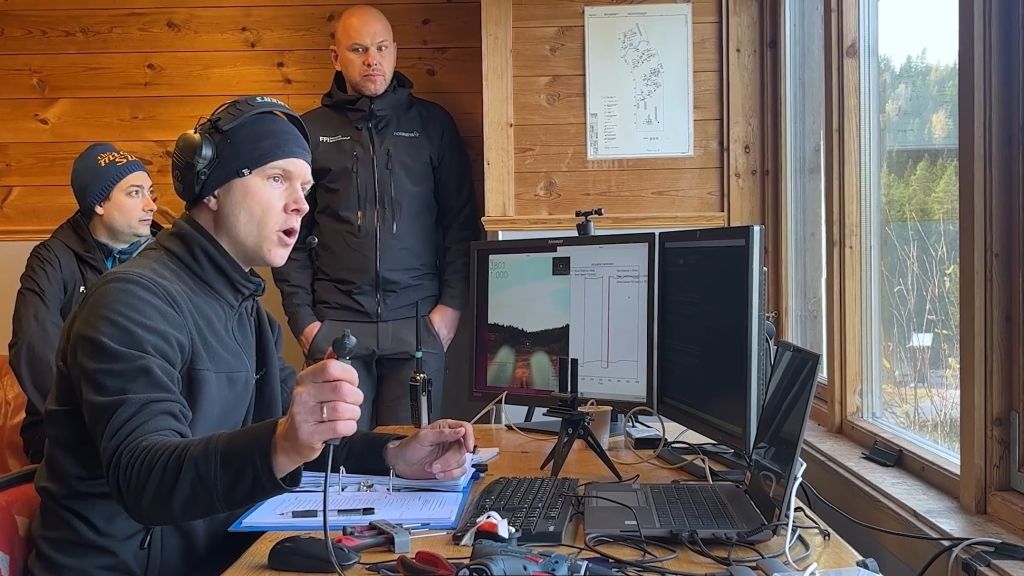 Tre forskere i et kontrollrom gjør seg klar til å avfyre et testvåpen. Mannen i forgrunnen har fingeren på en knapp og teller ned for å fyre av.