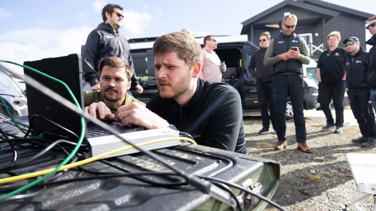 To forskere bak en PC med flere forskere i bakgrunnen. 