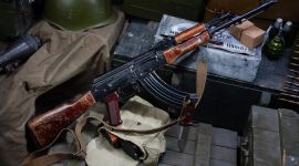 Kalashnikov AK 47 med ammunisjon på en militærgrønn boks bakgrunn. Tekst på ammunisjonsboksen på russisk - patron type og kaliber med partinummer.