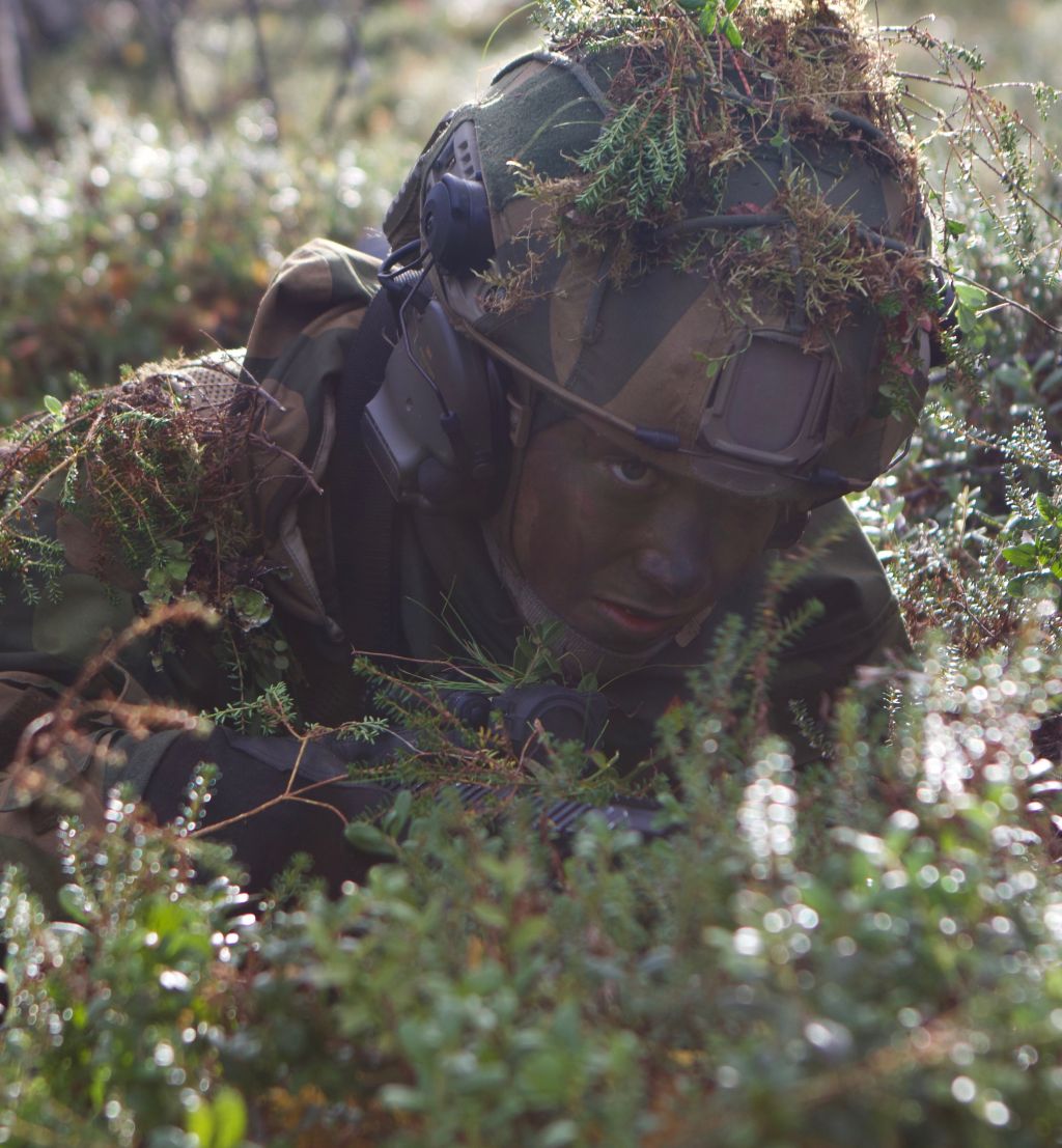 Soldat som kryper på bakken i kamuflasje