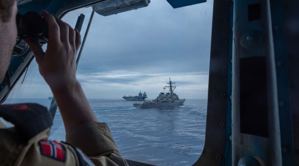 En soldat bruker kikkerten og ser to marinefartøy foran seg.