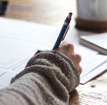 Nærbilde av hånd som skriver på papir med penn