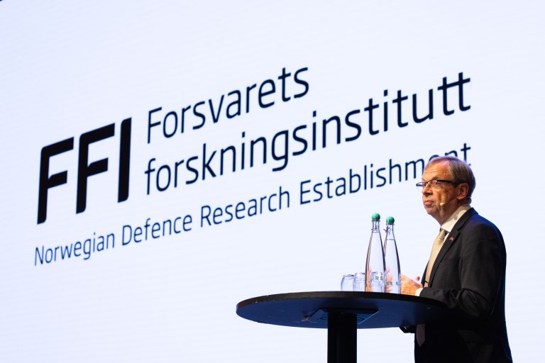 Mann i dress med FFI-logoen i bakgrunnen.