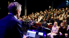 Forskningsdirektør Espen Skjelland på talarstolen framfor ein fullsett Deichmansal i Bjørvika i Oslo.