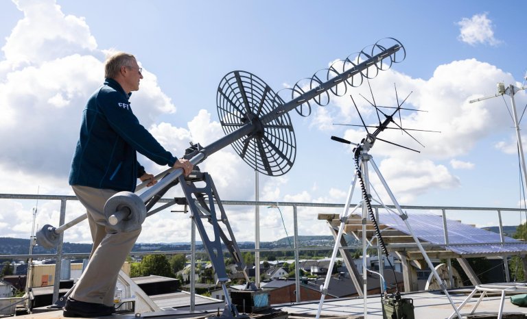 Lars Erling Bråten bak en antenne på taket av FFI på Kjeller.