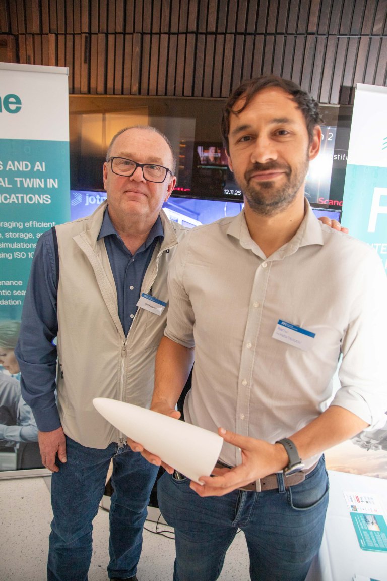 To menn viser fram ein kvit 3D-printa tupp.