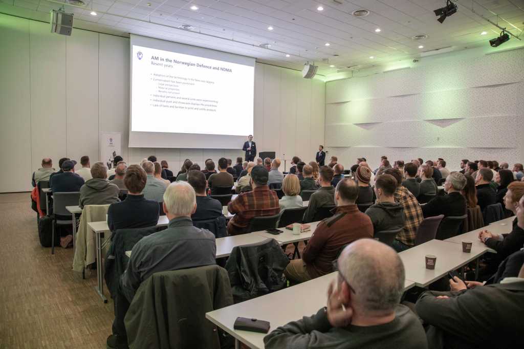 Publikum følger med på en presentasjon på storskjem.