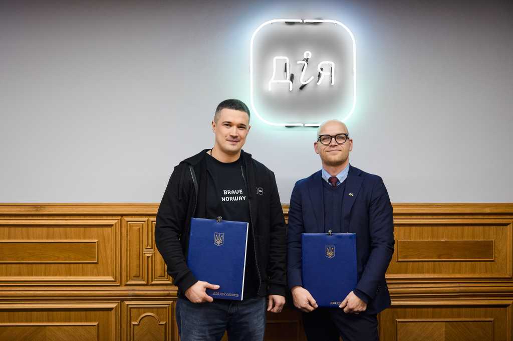 To menn holder hver sin mappe med samarbeidsavtale. Innendørs.