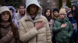 Sørgende ungdommer holder hånden til hjertet mens den Ukrainske nasjonalsangen spilles i en begravelse.