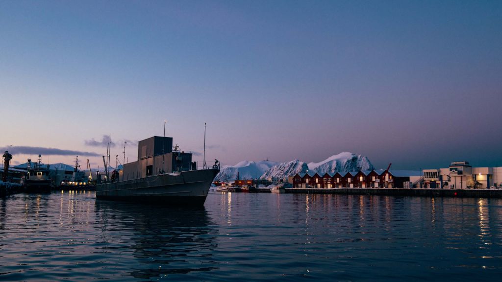 Testskip med kontainere med bebyggelse og fjell i bakgrunnen.