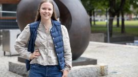 Ung kvinne står utendørs på en steinlagt plass