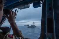 En soldat bruker kikkerten og ser to marinefartøy foran seg.