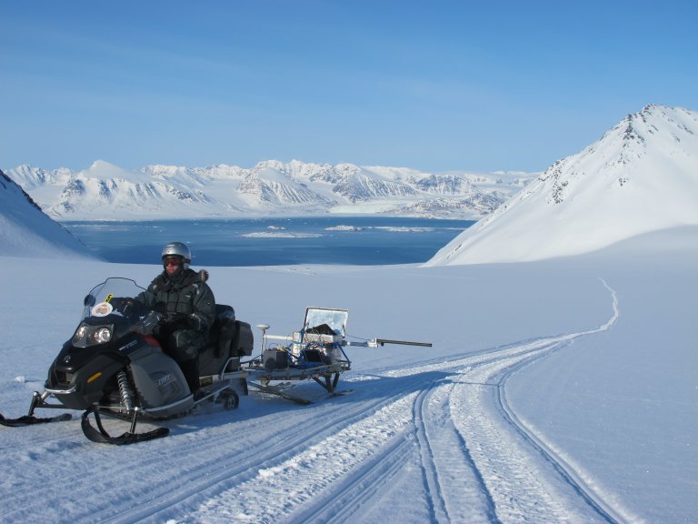 Snøskuter med slede kjører på isbree