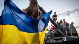 Jente holder Ukrainsk flagg. Unger og tenåringer klatrer på en beslaglagt Russisk stridsvogn som er utstilt på gaten i Kiev.