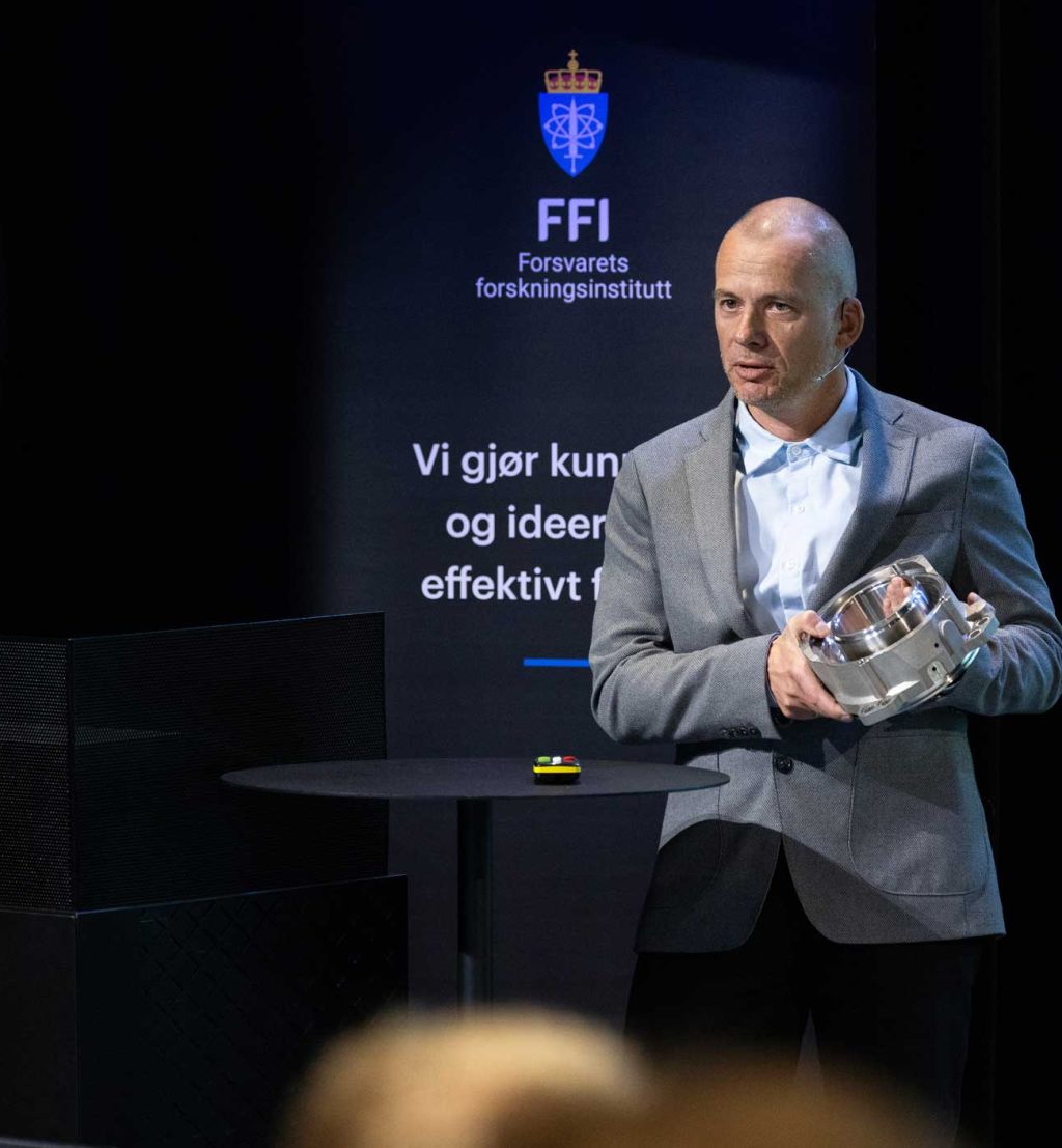 Bendik Sagsveen viser frem en 3D-printet del til et kjøretøy.
