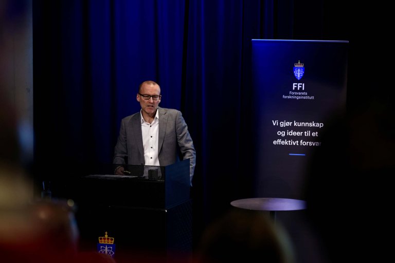 Brynjar Lia på scenen med FFI-banner i bakgrunnen.