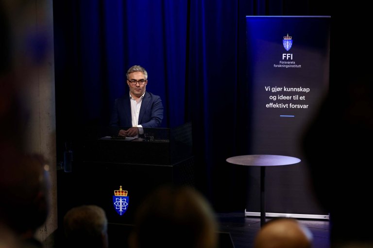 Truls H. Tønnesen på scenen med en FFI-banner i bakgrunnen.