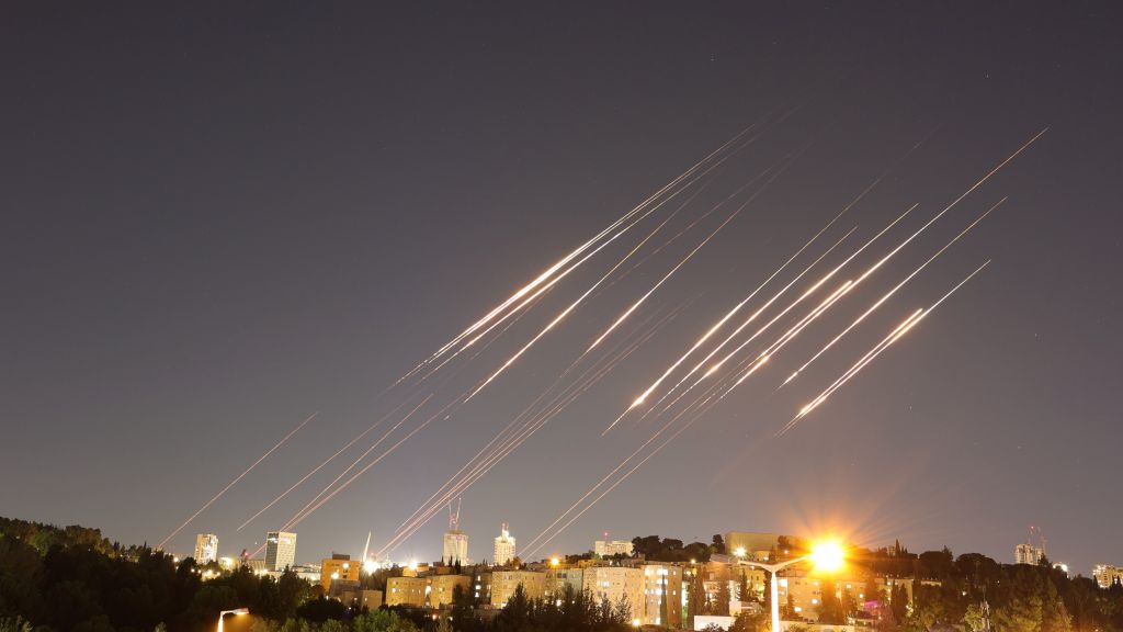 Lysstriper etter ballistiske missiler over himmelen . Bildet er tatt på natten. I nederste kant av bildet ser vi trære, bygniger og gatelys i  Jerusalem