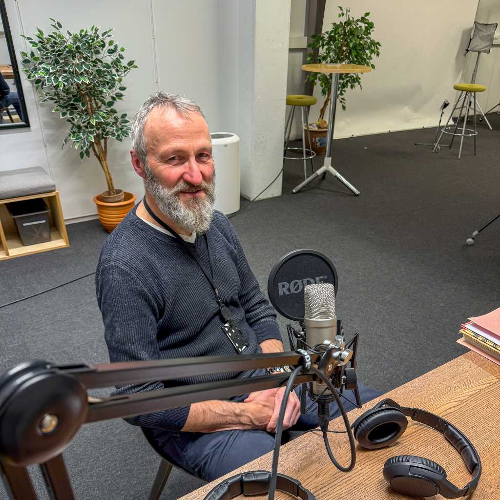 Forsker bak mikrofonen i podkaststudio.