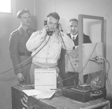 Fra utviklingen av et telesamband. Tre forskere bak en radio.