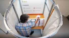 Mann i et valgavlukke skriver på en stemmeseddel.