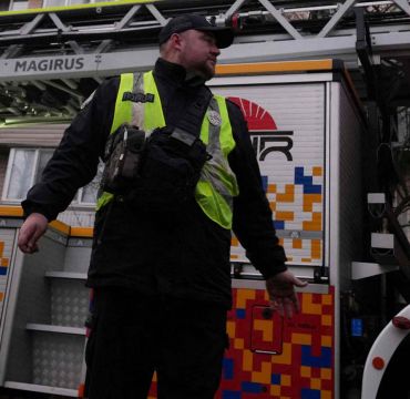 En politimann står foran en brannbil.