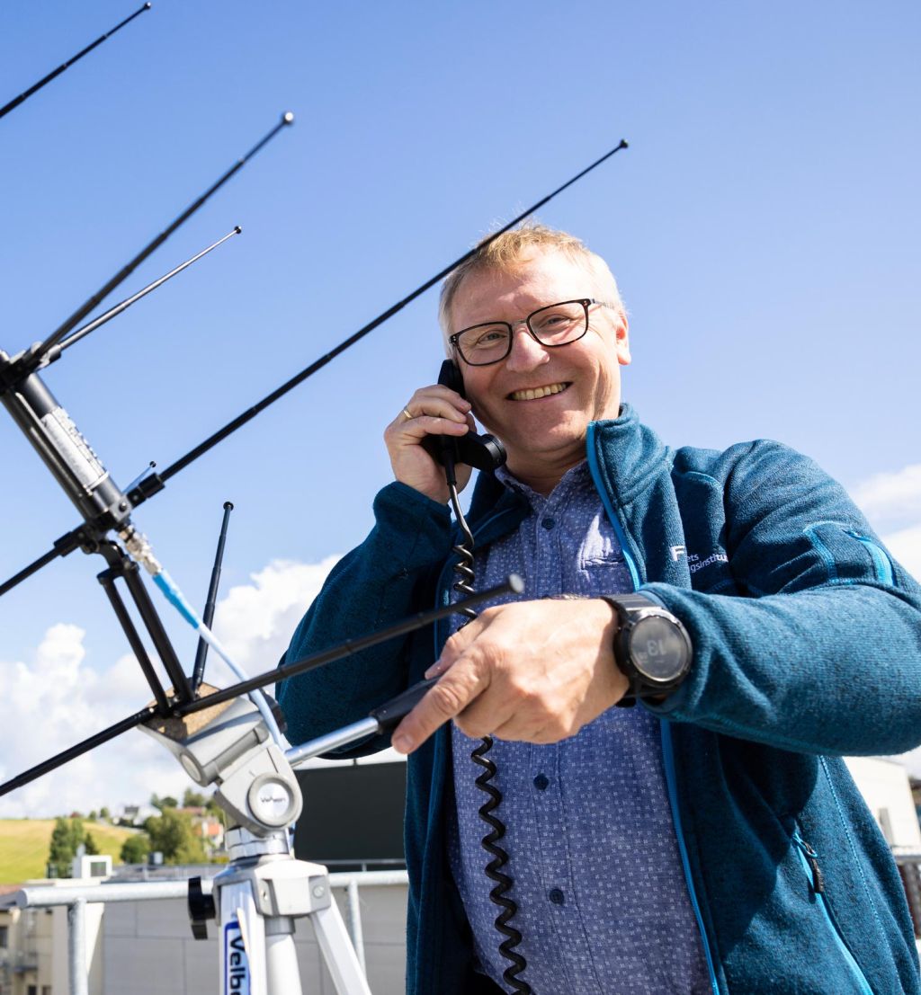 Lars Erling Bråten på taket av FFI på Kjeller med en antenne.