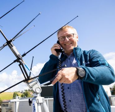 Lars Erling Bråten på taket av FFI på Kjeller med en antenne.