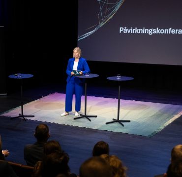 Guri Melby på scenen i blå drakt under Påvirkningskonferansen 2025.