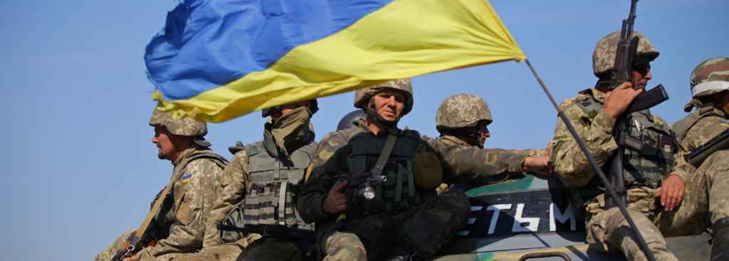 Soldater sitter på tanks med ukrainsk flagg. Foto