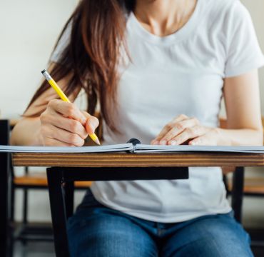 Jente sitter ved pult og skriver i ei bok